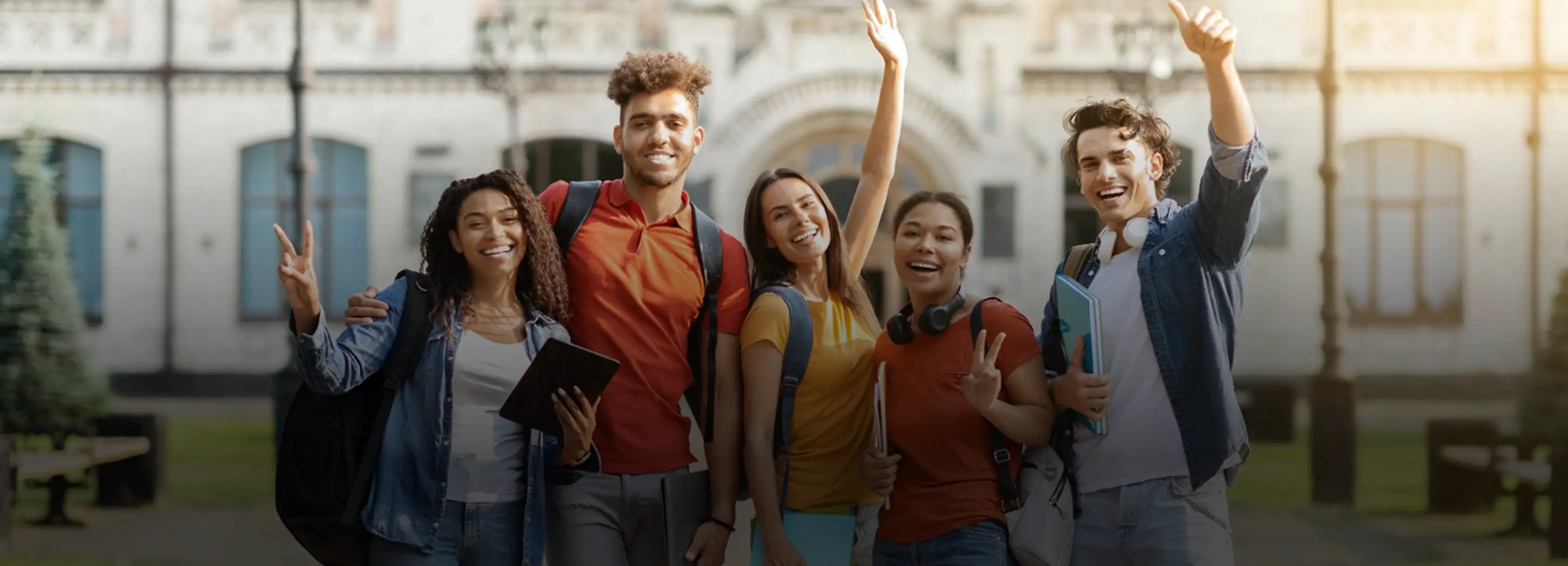 Group of happy students celebrating outside a university building